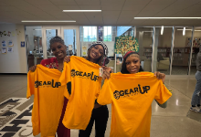 Three students holding yellow shifts that say "GEAR UP"