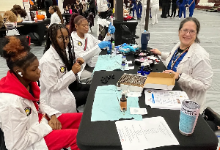 A career and technical education fair taking place in the Maple Heights High School gymnasium, identifiable by the "HOME OF THE MUSTANGS" banner and maroon school colors. 