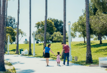 Parents walking with a child hand in hand down path on a sunny day
