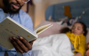 father reading a book to his daughter at bedtime