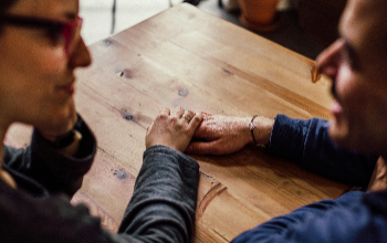 Friends holding hands sitting at a table