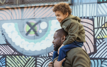 Dad with son on his back in front of mural